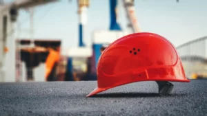 Casque de chantier rouge posé au sol, symbolisant un ouvrier ayant quitté le chantier dans le cadre d’un droit de retrait pour danger grave et imminent.