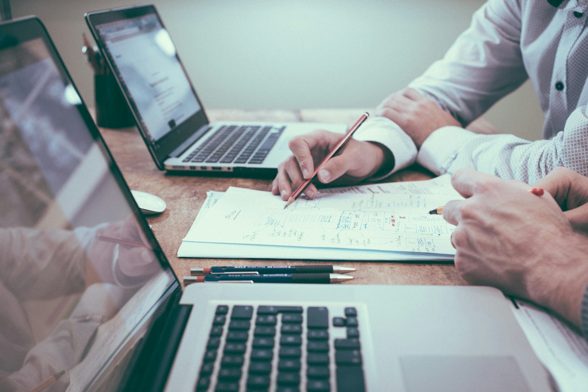 deux personnes dont on voit les mains posées sur un bureau. Elles travaillent sur un audit flash grâce à des ordinateurs portables et des documents.