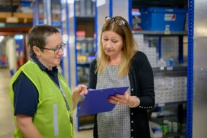 Deux professionnelles analysent un document de contrôle dans un entrepôt.
